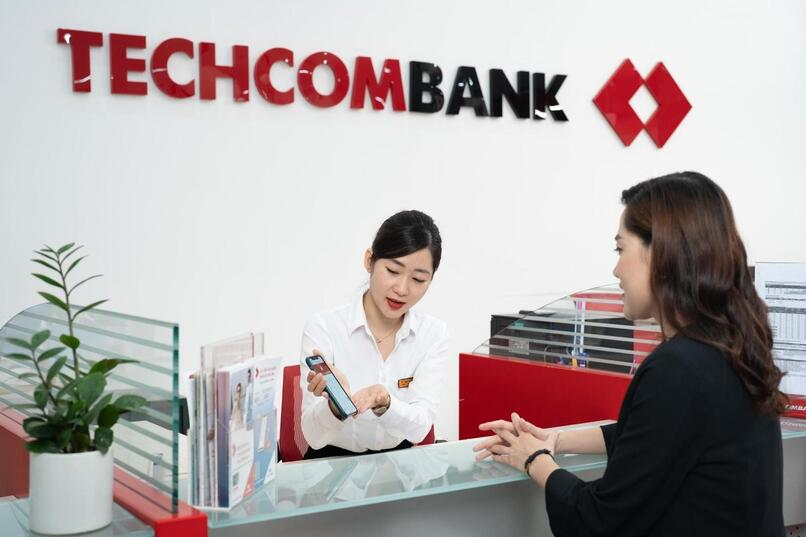 Giao dịch viên Techcombank hướng dẫn khách hàng thủ tục gửi tiết kiệm tại ngân hàng.