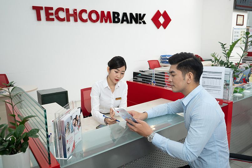Tư vấn viên Techcombank hướng dẫn khách hàng mở thẻ thanh toán quốc tế tại quầy giao dịch 