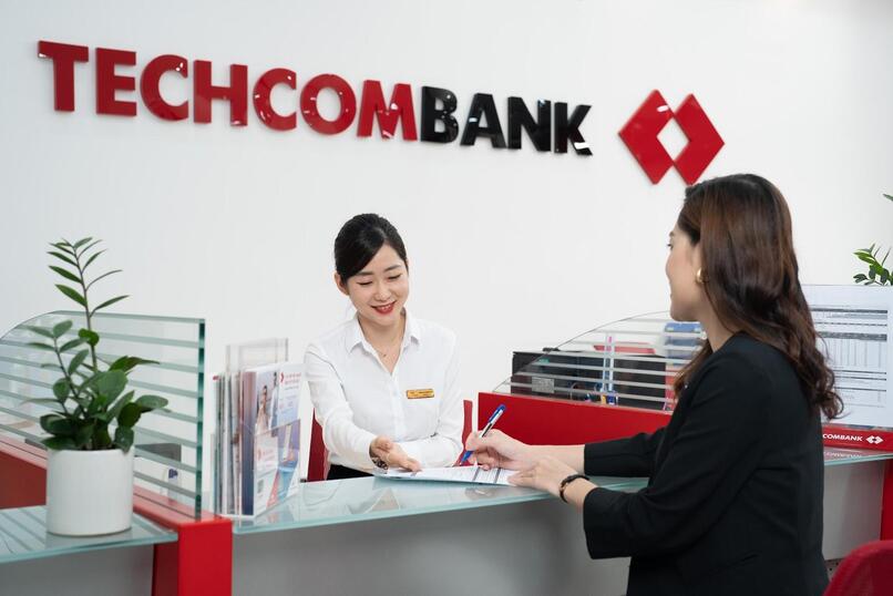 Giao dịch viên Techcombank hướng dẫn khách hàng mở tài khoản tiết kiệm.