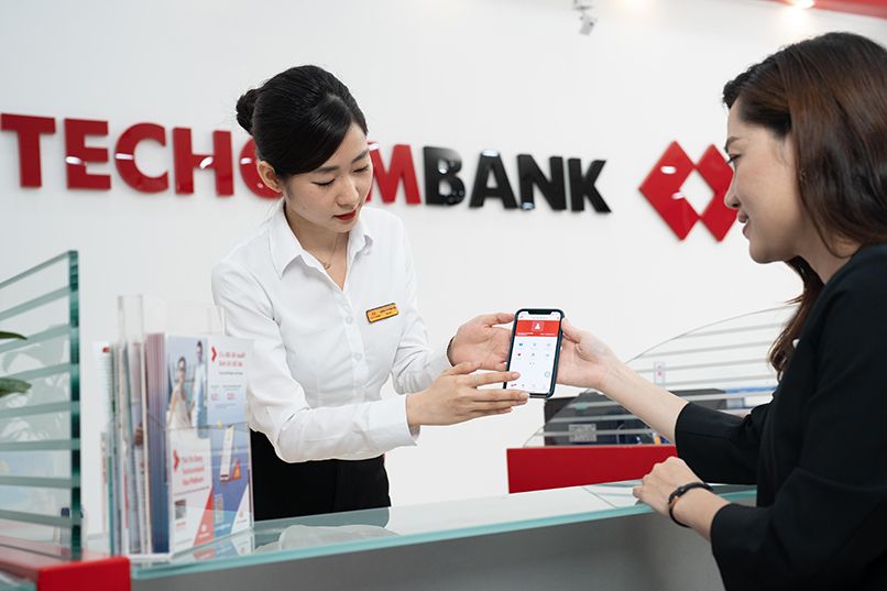 Tư vấn viên Techcombank hướng dẫn khách hàng chuyển tiền bằng thẻ ghi nợ tại quầy giao dịch